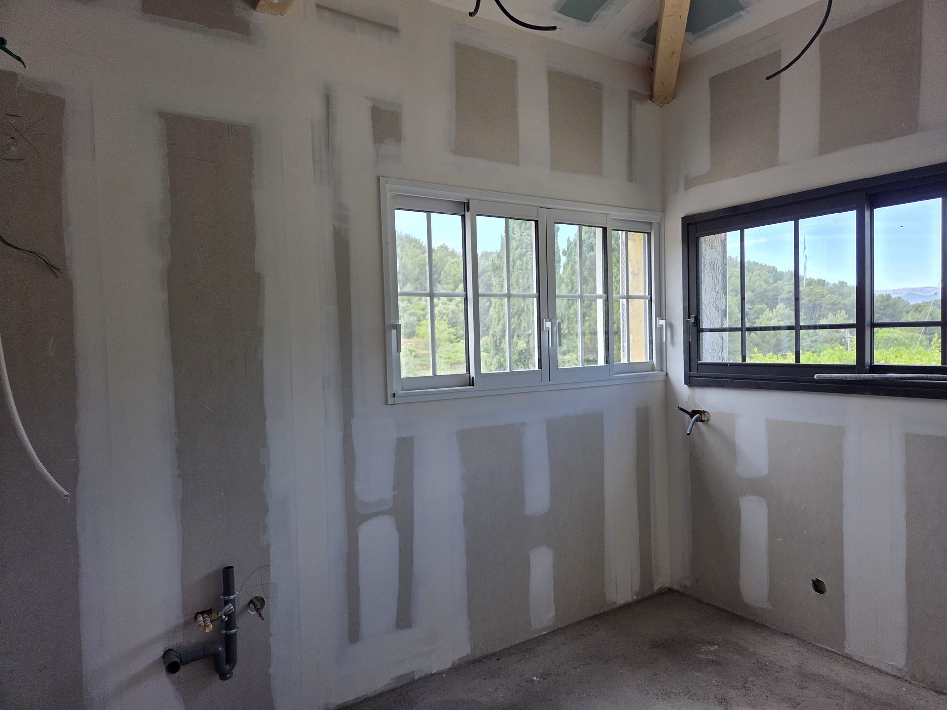 Pièce de villa neuve avec doublage placo, bandes et joints lissés et grandes baies aluminium ouvrant sur les collines du Var